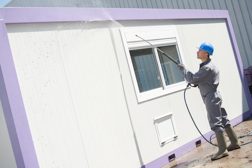 Man cleaning exterior of purple building 